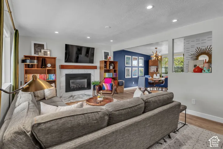 Recessed lighting illuminates the living area with a fireplace featuring a marble-finish surround and wood mantel