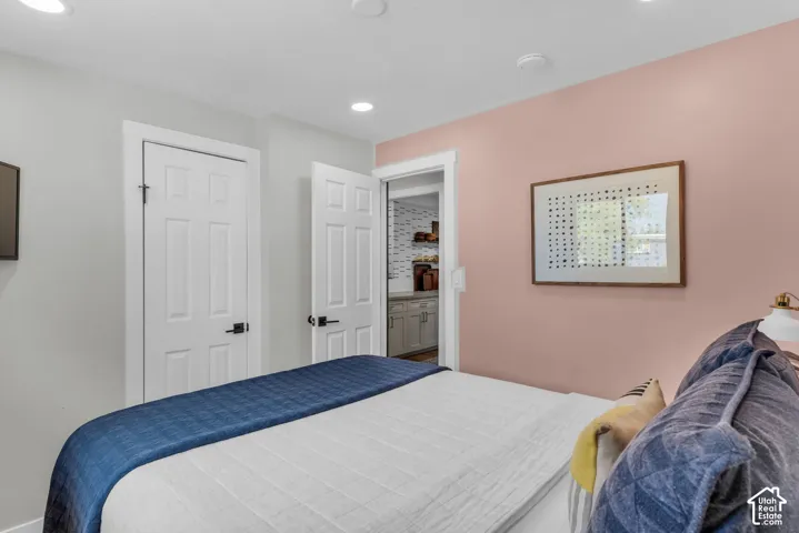 Recessed ceiling lighting, paneled interior doors with matte black hardware, and an entryway to an adjoining room with built-in cabinetry and open shelving