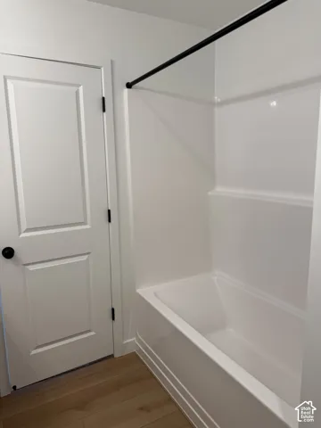 White acrylic bathtub with a matching shower surround and black shower rod
