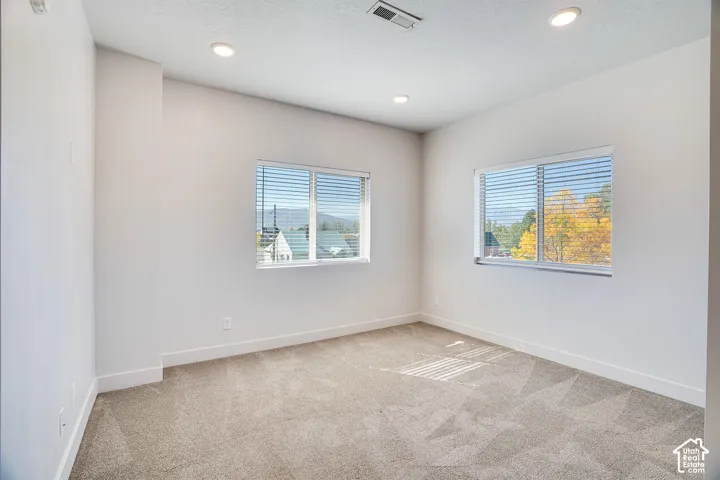 Recessed lighting, light-toned walls, and neutral carpeting