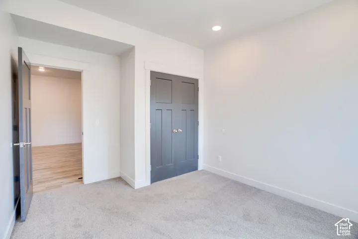 Gray carpeting, white walls, recessed lighting, dark paneled doors, and white trim