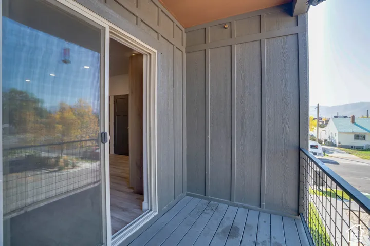 Balcony featuring composite decking, vertical board-and-batten style siding, and a metal grid railing