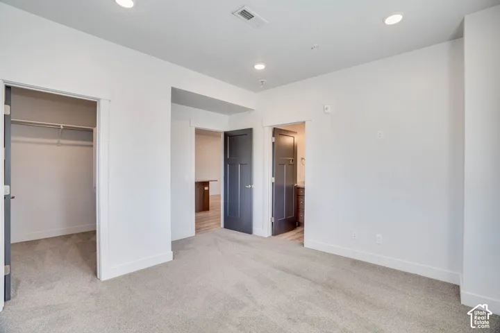 Recessed lighting illuminates the carpeted flooring and white wall finishes