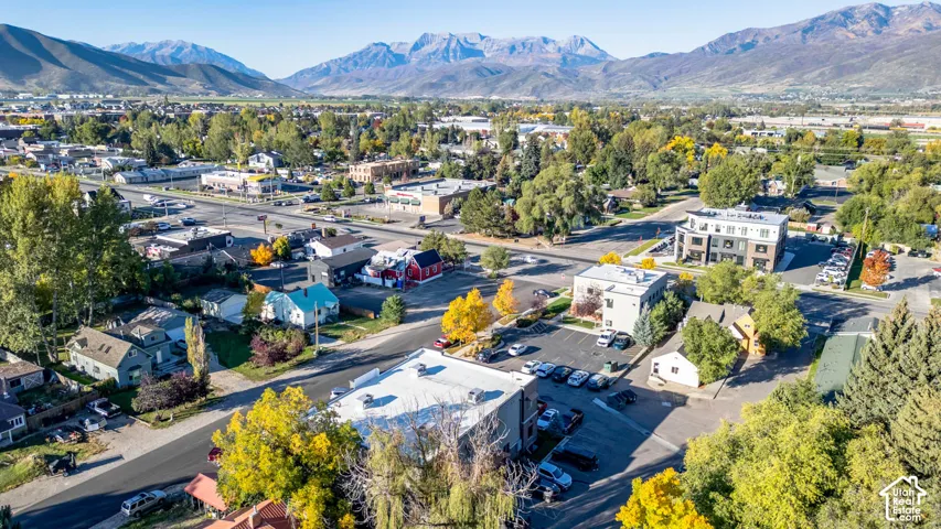 Mountain backdrop with a developed community, featuring a mix of residential and commercial structures, paved streets, and abundant mature trees