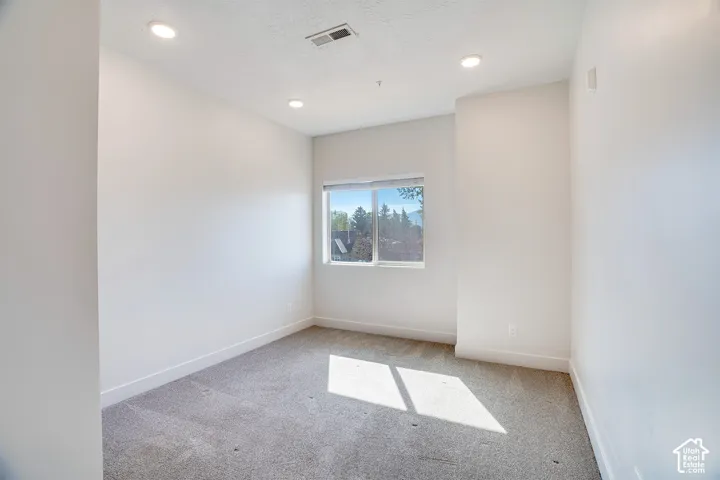 Recessed lighting, light gray carpeting, and a double-pane window