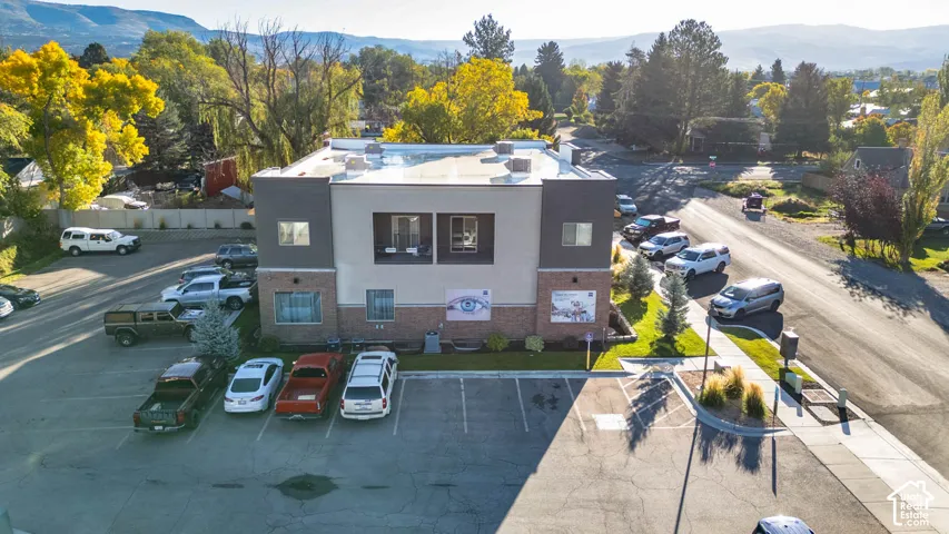 Modern commercial building with a multi-textured facade, featuring a paved parking lot and established landscaping