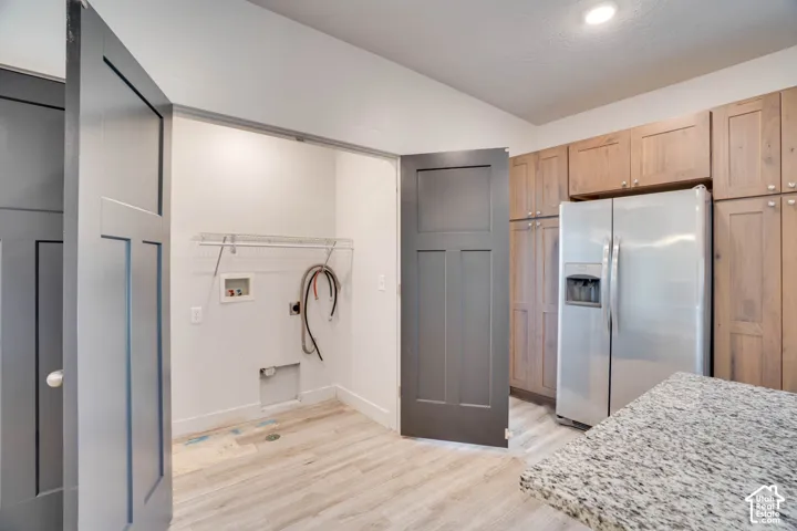 Laundry area with wire shelving, light wood-finish flooring, and gray panel doors