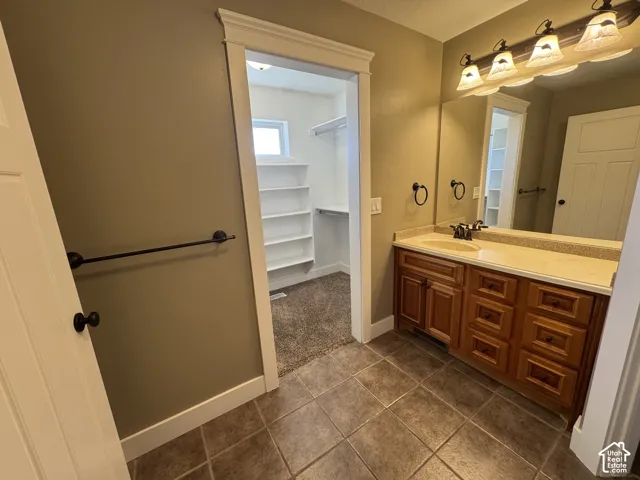 Bathroom featuring a wood-finish vanity with an integrated sink and a light-toned countertop