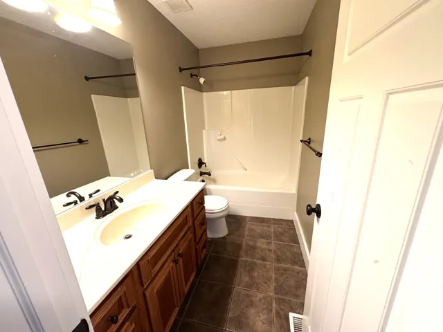 Bathroom featuring a single vanity with wood-finish cabinetry, a drop-in sink, and a white countertop