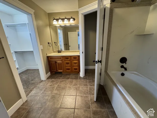 Tiled flooring with a single vanity featuring a wood-finish cabinet, wall-mounted mirror, and decorative light fixture