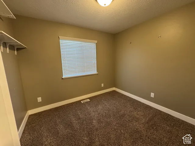 Room featuring wall-to-wall carpeting, a window with horizontal blinds, overhead lighting, and built-in shelving