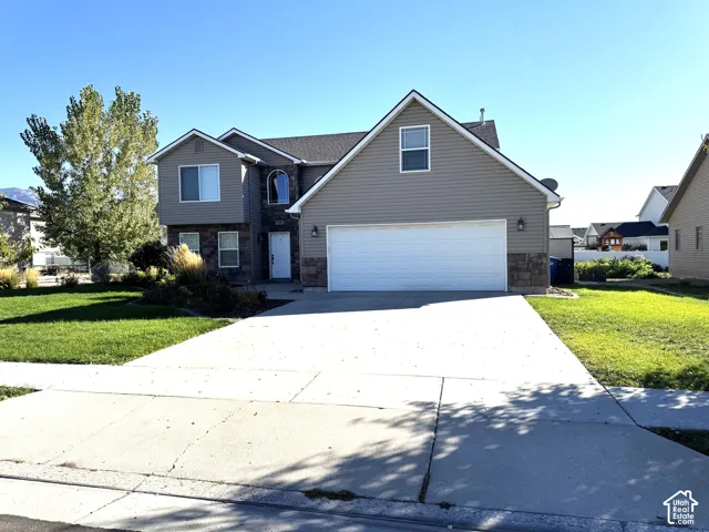 Two-story exterior with siding and stone accents, featuring a two-car garage, established front landscaping, and a concrete driveway