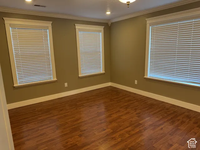 Wood-finish flooring with crisp white trim, crown molding, and recessed lighting