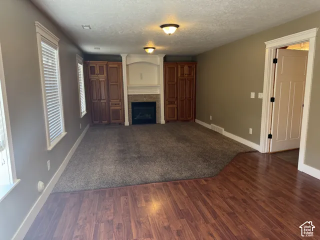 Built-in cabinetry flanking a fireplace with a stone surround, recessed lighting, and wood-finish flooring
