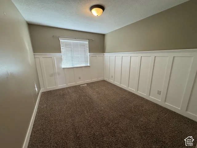 Neutral-toned wall paint, white wainscoting, textured carpet flooring, and a flush-mount ceiling light