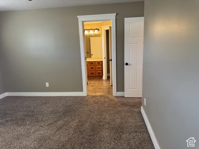 Carpeted room with a doorway featuring white trim and a paneled door