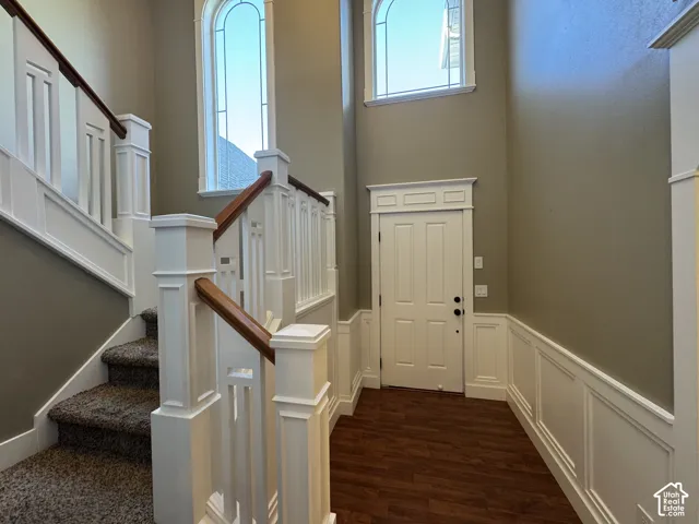 Two-story entryway with two arched transom windows, white wainscoting, and wood-finish flooring