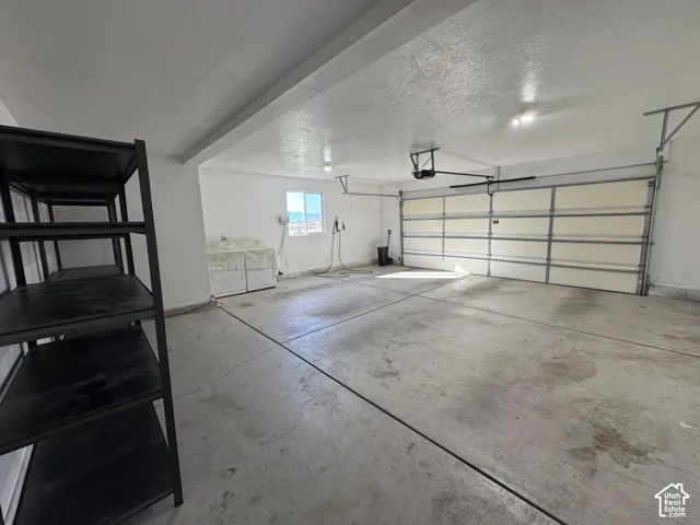 Spacious garage with concrete flooring, automatic garage door, and a window for natural light
