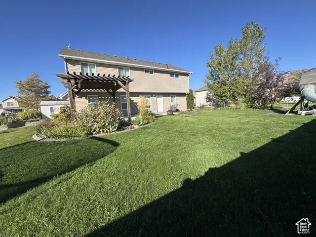 Expansive green lawn with a pergola and mature trees