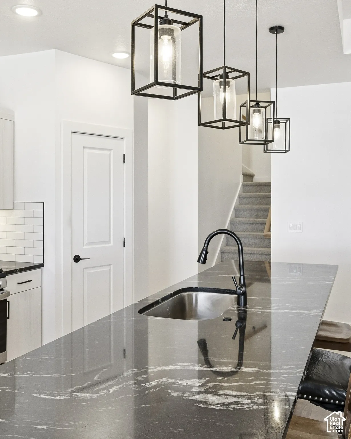 Waterfall edge island with dark veining, undermount stainless steel sink, and a matte black pull-down faucet