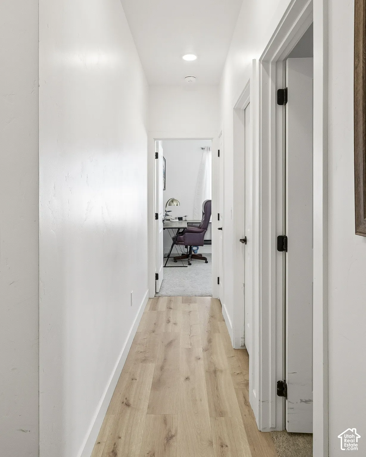 Hallway with wood-finish flooring, recessed lighting, and white walls