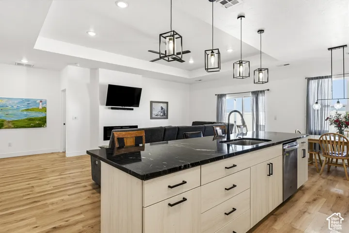 Spacious kitchen island with dark stone countertop, undermount sink, and light wood-finish cabinetry with dark hardware