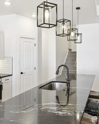 Waterfall edge island with dark veining, undermount stainless steel sink, and a matte black pull-down faucet