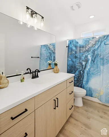 Extended vanity with wood-finish cabinetry, solid surface countertop, and integrated sink