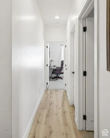 Hallway with wood-finish flooring, recessed lighting, and white walls