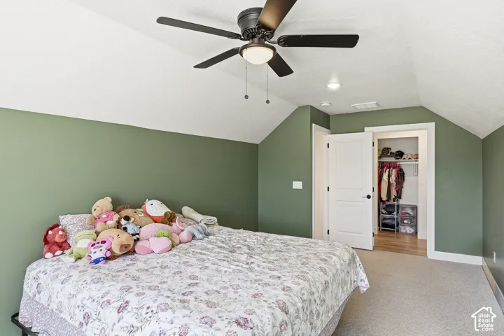 Sloped ceilings with recessed lighting, black ceiling fan with integrated light, warm green wall accents, white trim, and a built-in closet with hanging rod