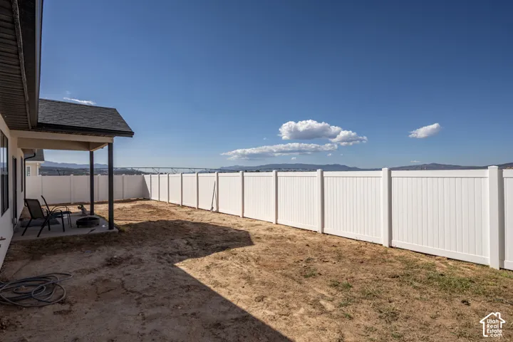 Expansive backyard space with a white privacy fence and a covered patio area