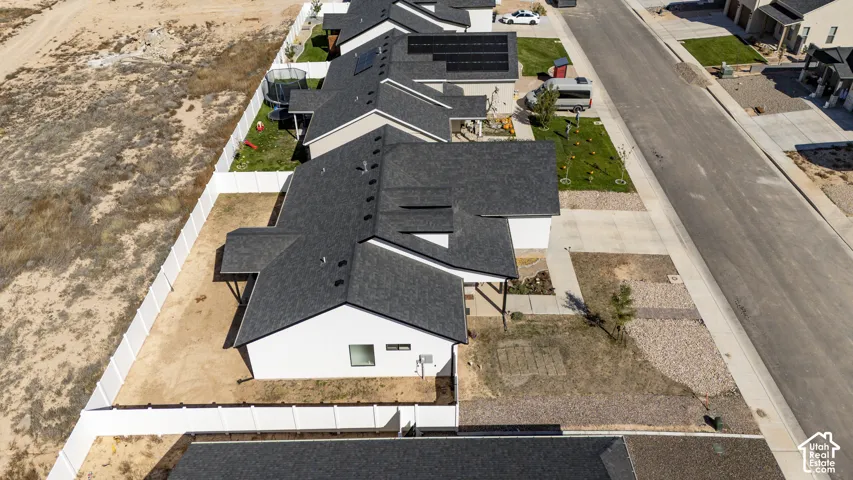 Newly constructed residential property featuring a dark shingle roof, white exterior siding, and a fenced backyard