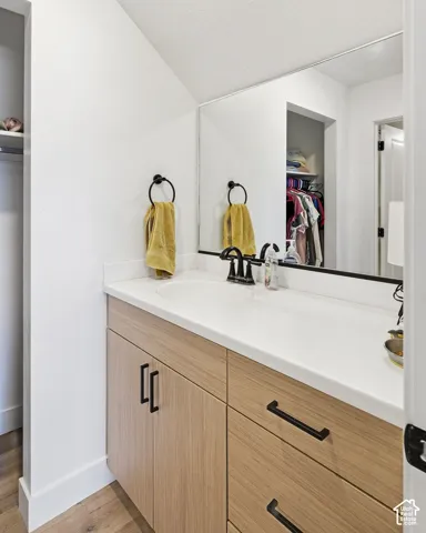 Wood-finish vanity with black hardware, white countertop, and an integrated sink with a black faucet