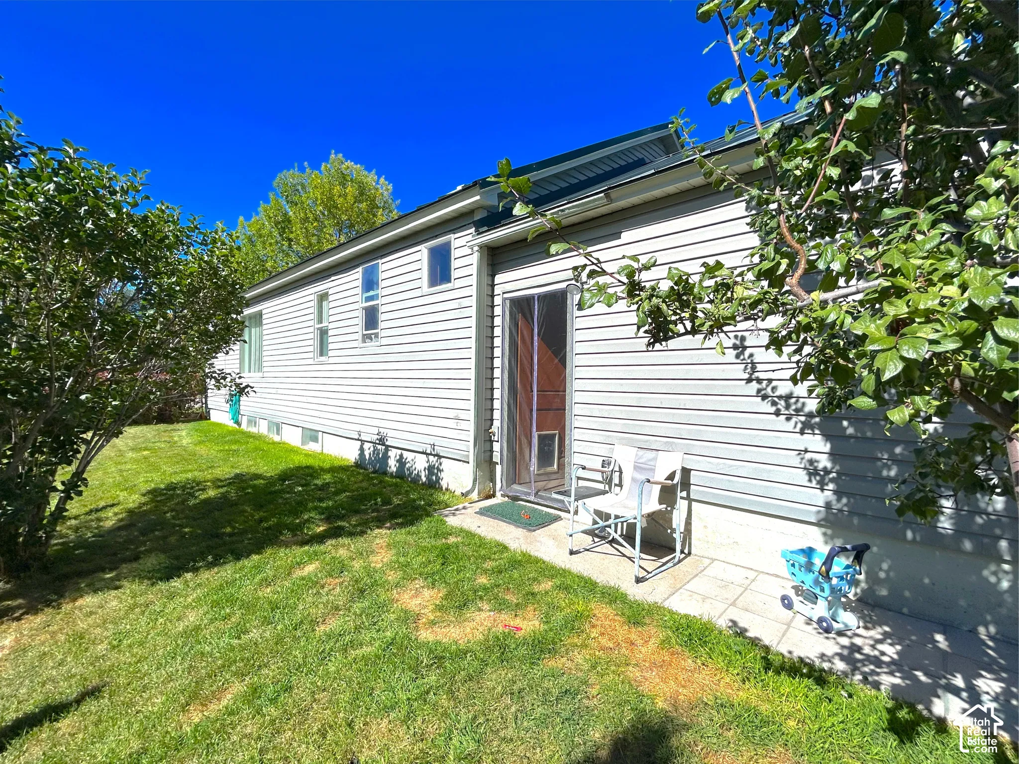 Side exterior with horizontal siding, multiple windows, and direct patio access