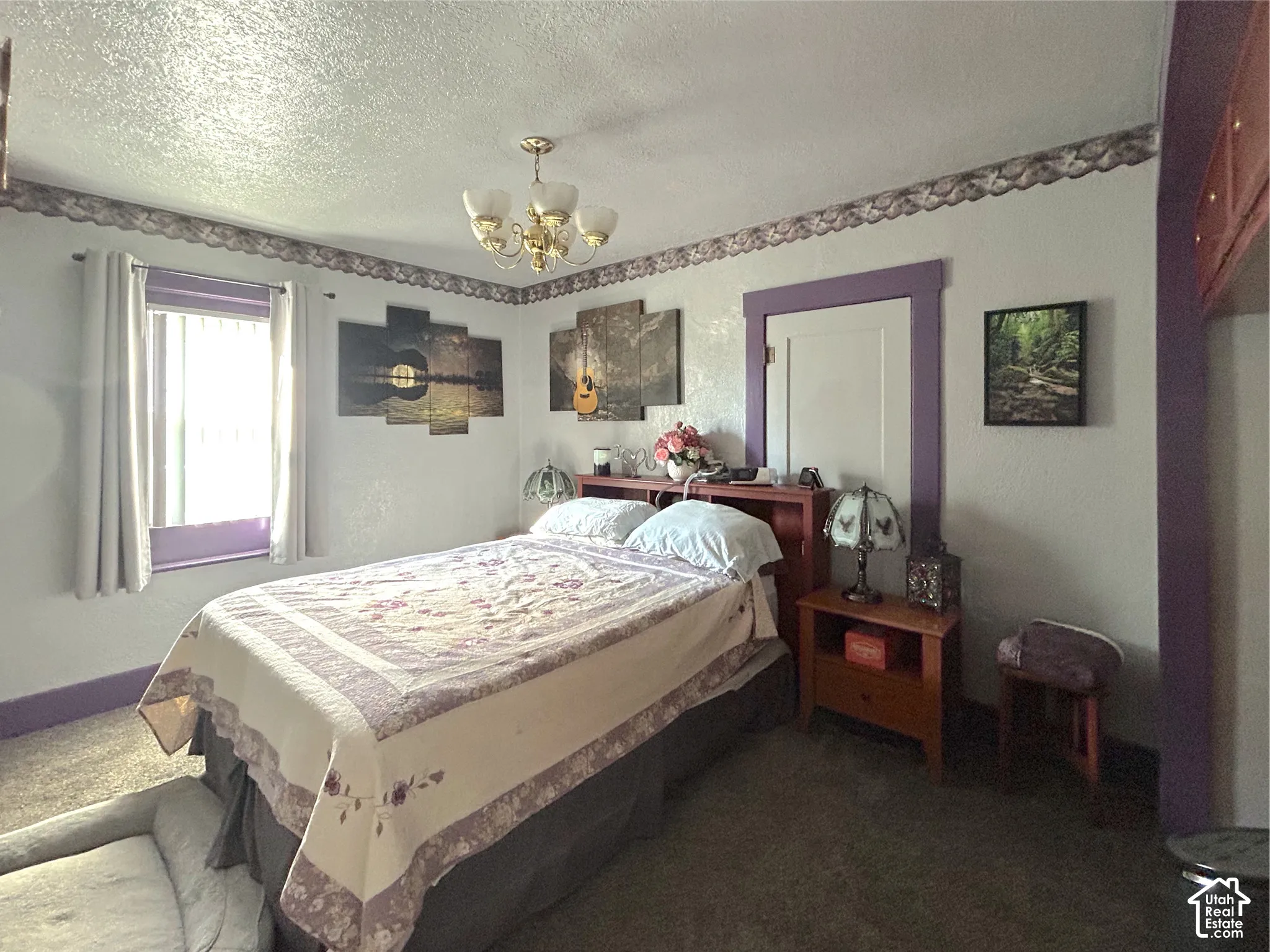 Window with purple trim, a gold-toned chandelier, and a wood-finish headboard