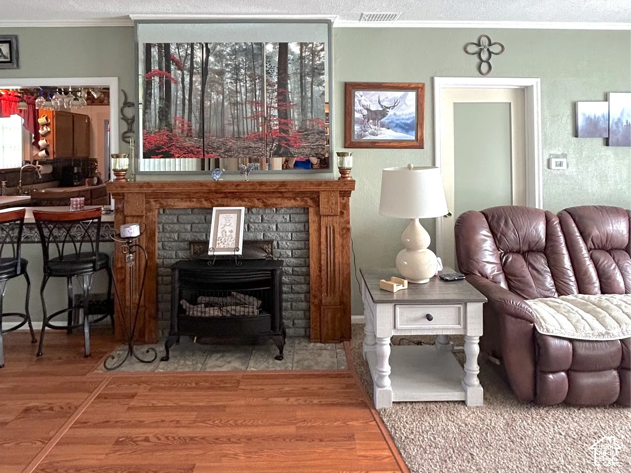 Wood-finish flooring, stone-front fireplace, wood mantel, and crown molding