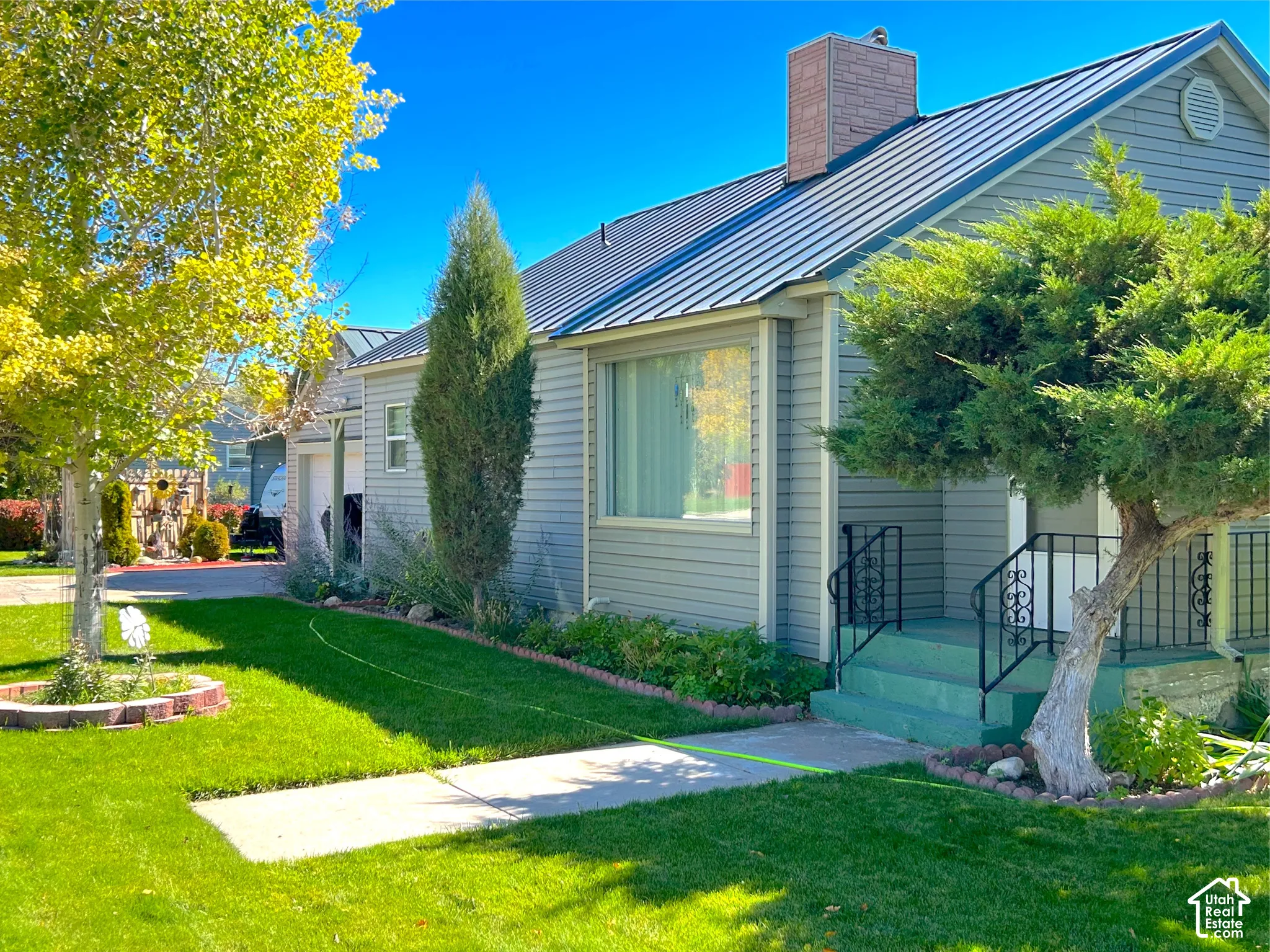 Light gray horizontal siding exterior with a metal roof and brick chimney