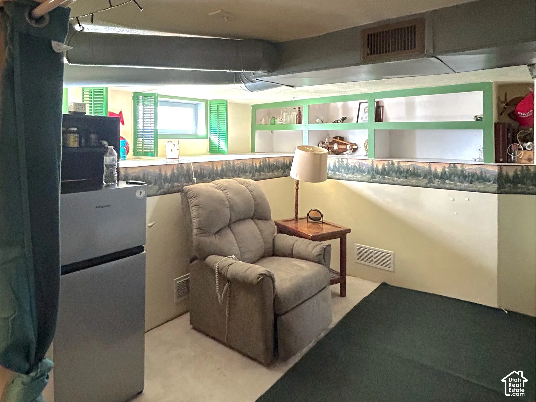 Built-in shelving, painted window shutters, overhead ductwork, and ceiling-mounted track lighting in the basement den area.