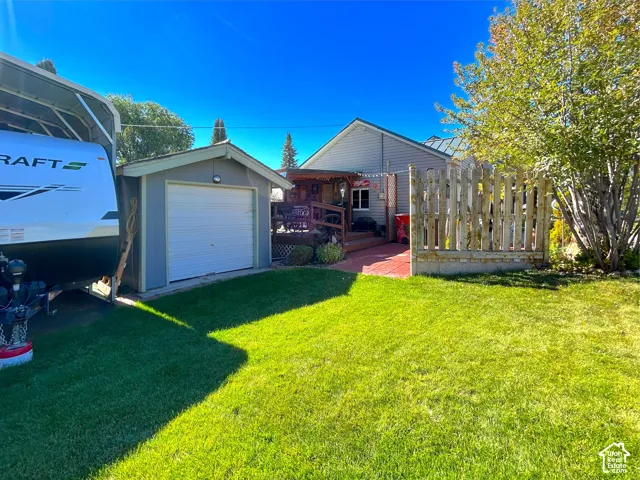 Expansive green lawn, detached storage shed with roll-up door, wooden deck, and privacy fence