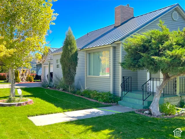 Light gray horizontal siding exterior with a metal roof and brick chimney