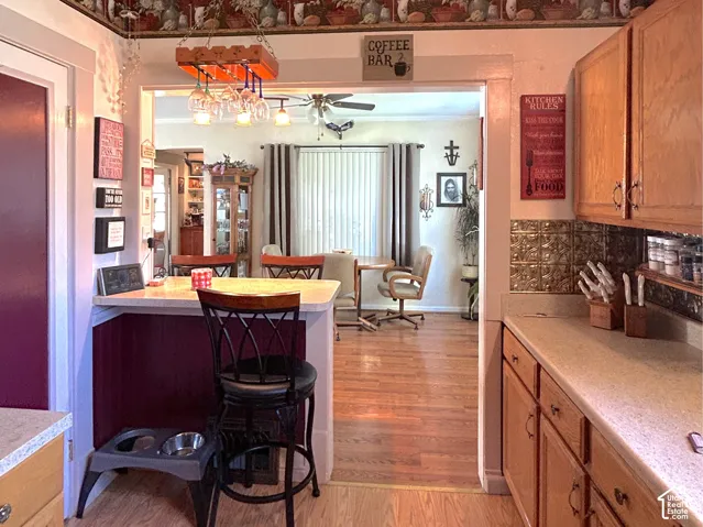 Kitchen featuring wood-finish flooring, light wood cabinetry, and a textured backsplash