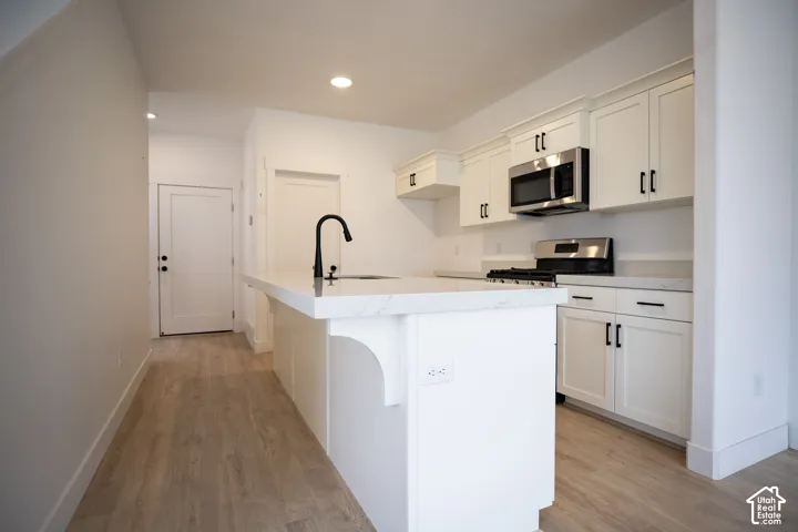 Terrific kitchen with painted white wood cabinets, quartz slab countertops, walk-in pantry, gas range, microwave, dishwasher and disposal.