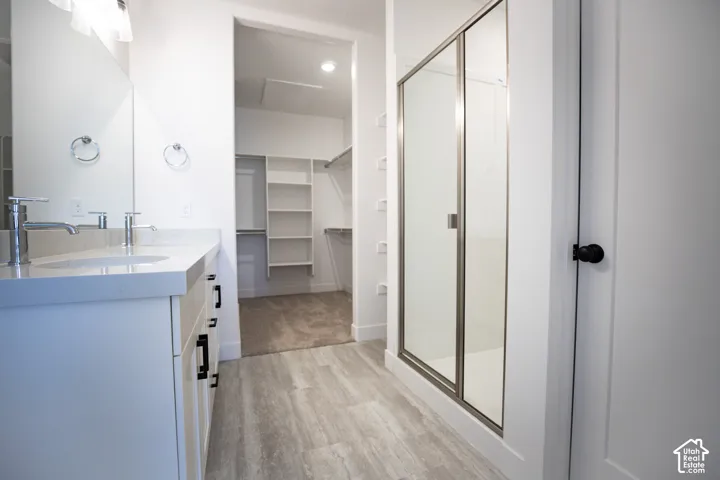 Primary bathroom with dual sinks, painted white wood cabinets, quartz slab countertops and large walk-in shower.