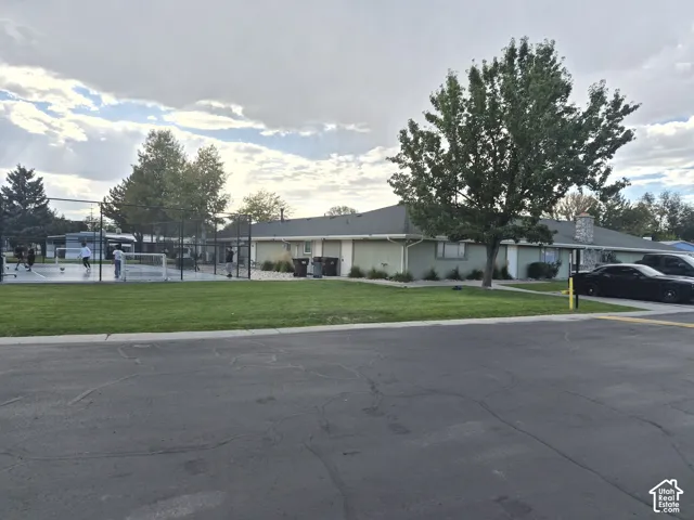 Expansive green space featuring a multi-sport court with surrounding fencing, a manicured lawn, and mature trees
