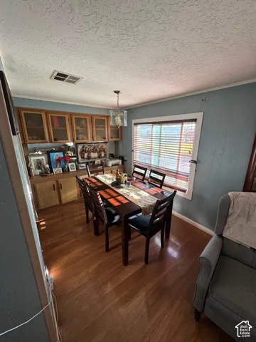 Dining area featuring wood-finish flooring, built-in wooden cabinetry with glass-front uppers, and a hanging light fixture