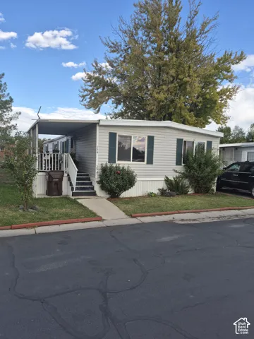Siding exterior with multiple windows, covered porch, and landscaping