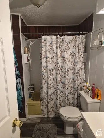 Wood-finish flooring with a toilet and a shower-over-tub combination