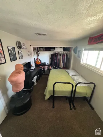 Interior room featuring wall-to-wall carpeting, a horizontal sliding window, and a built-in closet with overhead shelving and a hanging rod