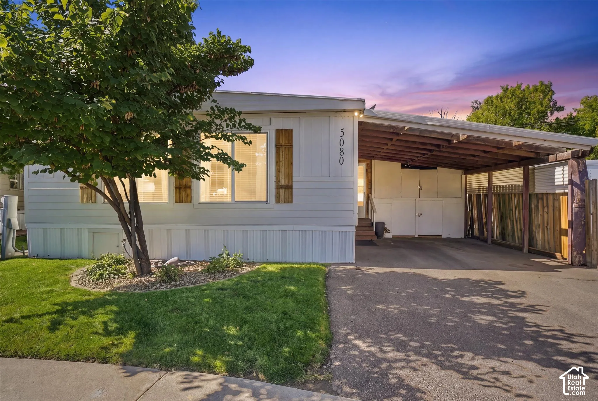 White exterior with wooden shutters and a carport