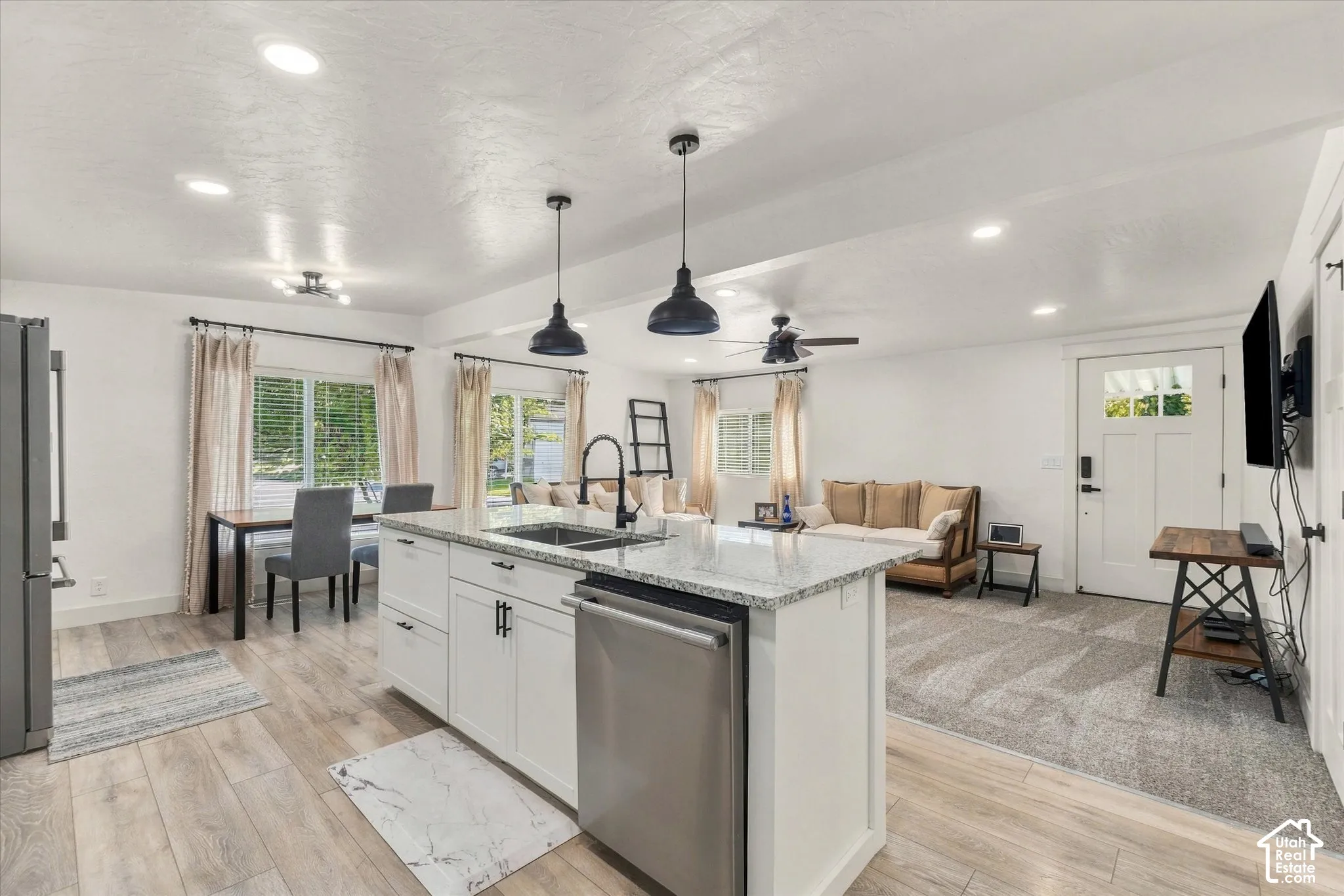 Open-concept layout featuring wood-finish flooring, recessed lighting, and a modern kitchen island with integrated sink